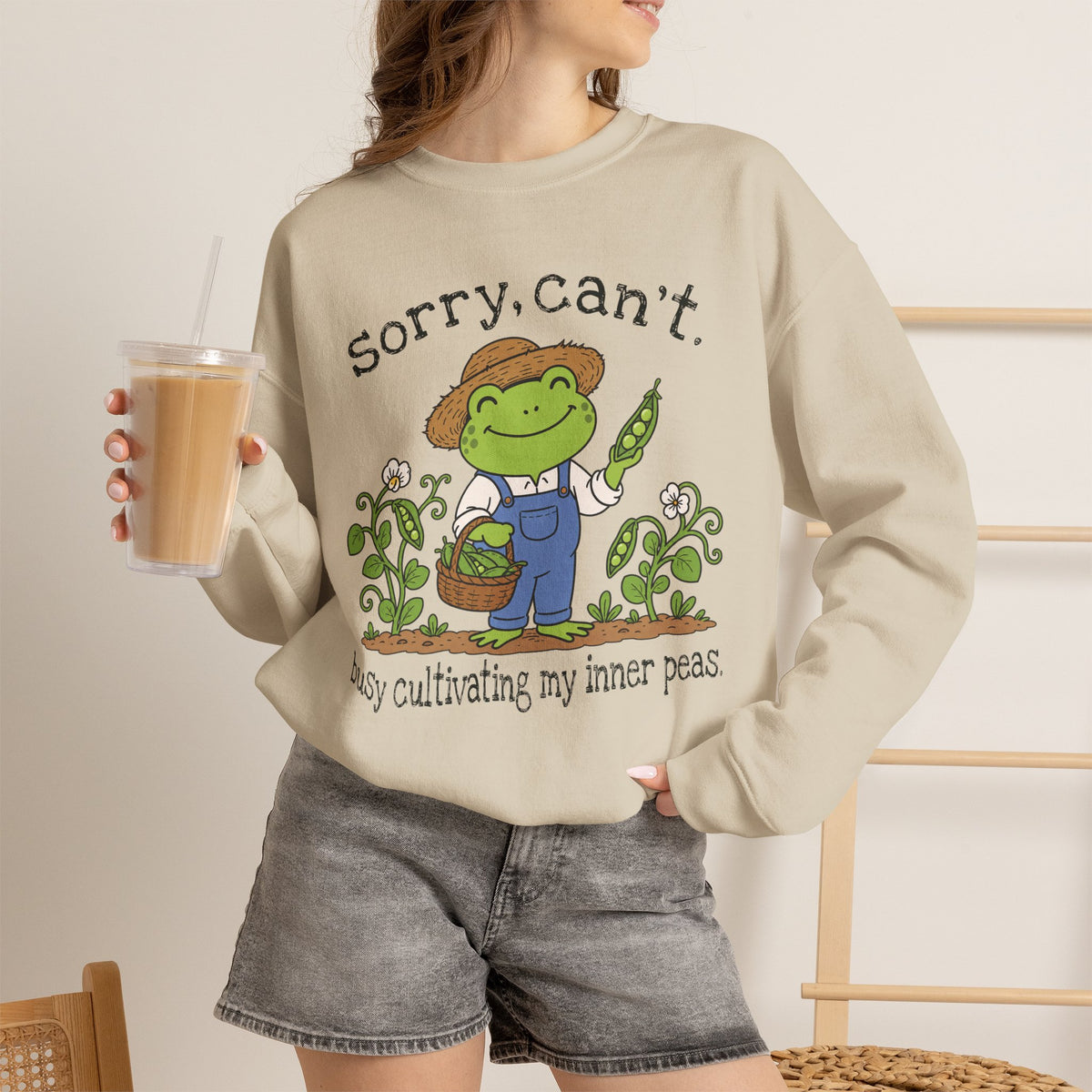 Lifestyle mockup of the Sorry Can't Busy Cultivating My Inner Peas frog Gildan 18000 sweatshirt.